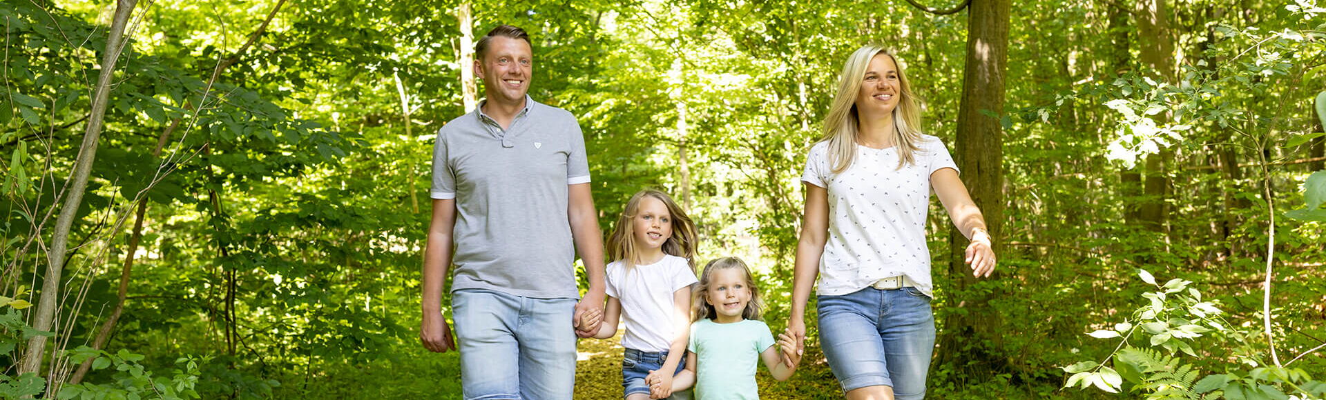 Eltern spazieren mit Ihren beiden kleinen Töchtern durch den Bienenwald des Wildparks Knüll.